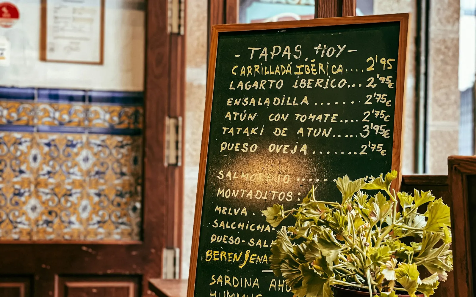 Barra de un bar de tapas con pizarra y azulejos